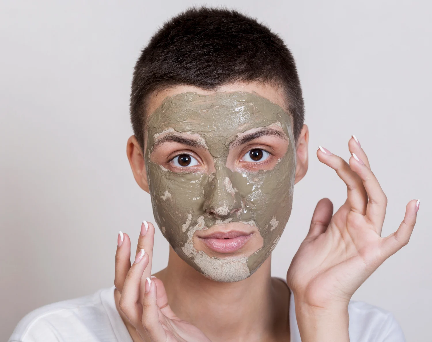 Person applying a clay mask to the face, demonstrating oil control for combination skin in humid weather